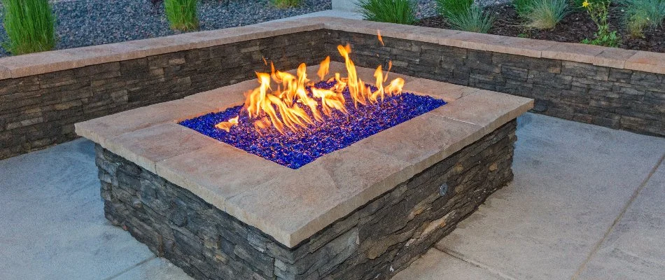 A gas-burning stone fire pit with a seating wall in Las Cruces, NM.