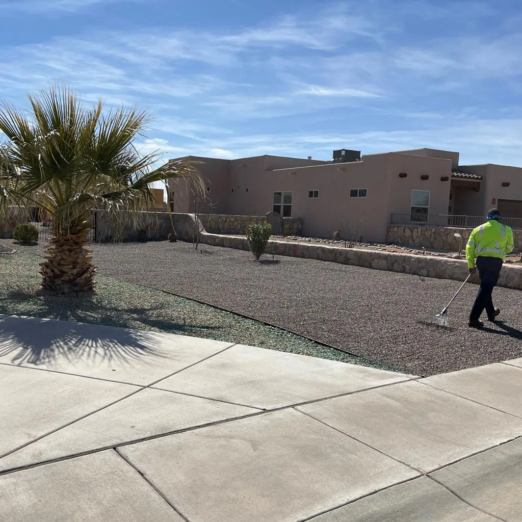 Expert maintaining newly installed rock ground covering in Las Cruces, NM.